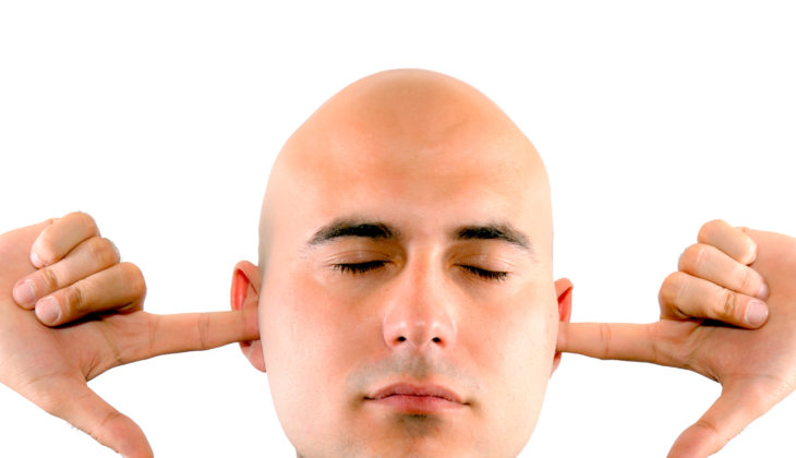 man with fingers in ears not listening